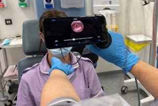 Person examining a patient's neck with an iPhone using the endoscope-i app
